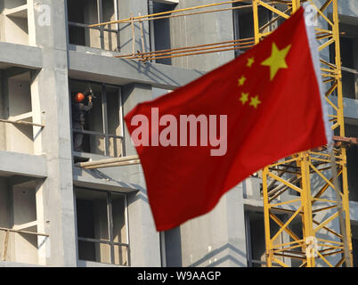 --FILE--A Chinese flag flutters in front of a residential apartment building under construction in Nanjing city, east Chinas Jiangsu province, 31 Octo Stock Photo