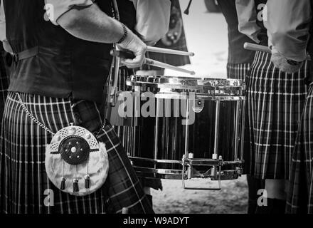 Closeup of the traditional Scottish drum and the hands of a drummer wearing kilt in Scottish band playing outdoors. Stock Photo