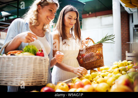 Young happy women shopping vegetables and fruits on the market Stock Photo