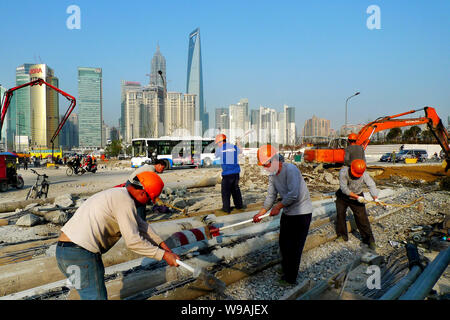 --FILE--Chinese migrant workers labor at a construction site near the Bund against the skyline of Pudongs Lujiazui Financial District in Shanghai, Chi Stock Photo