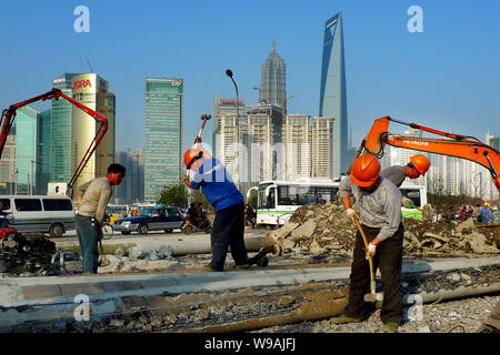 --FILE--Chinese migrant workers labor at a construction site near the Bund against the skyline of Pudongs Lujiazui Financial District in Shanghai, Chi Stock Photo