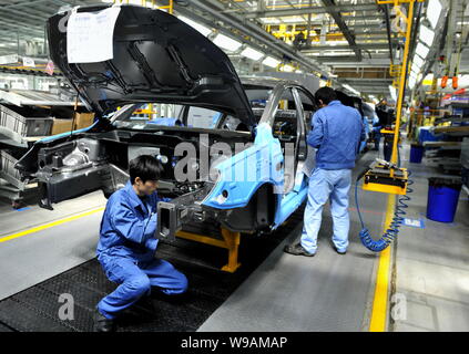 Chinese factory workers assemble Roewe 350 cars on the assembly line at the auto plant of SAIC in Nanjing city, east Chinas Jiangsu province, 17 March Stock Photo