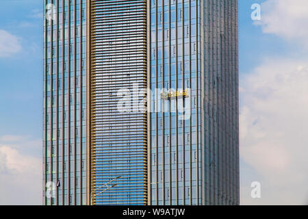 Workers in a hanging cradle wash windows in a modern office building Stock Photo