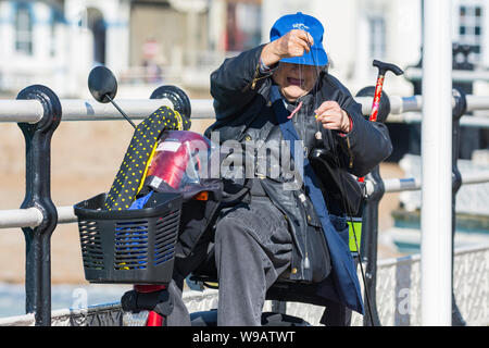 Active senior disabled woman in a mobility scooter preparing a fishing line. Stock Photo