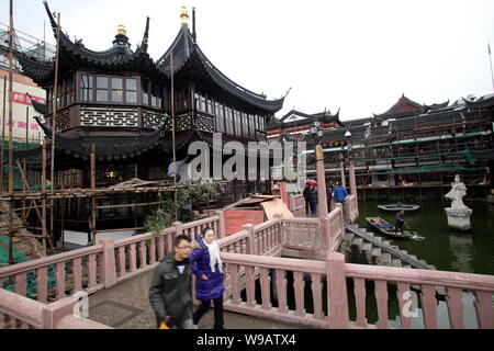 Chinese tourists walk on the Bridge of Nine Turnings (Jiuqu Bridge) in front of the renovated Huxingting Teahouse in the Yu Garden in Shanghai, China, Stock Photo