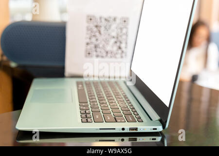 Business computer laptop on counter table with blur QR code in blur background. Stock Photo