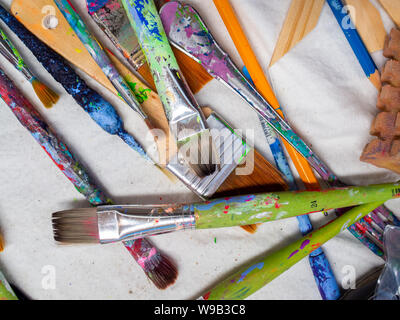 Artist paintbrushes. Flat lay of many artist tools on white fabric, art equipment. Stock Photo