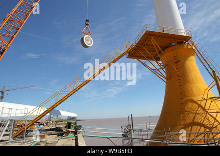 Chinese workers assemble a wind turbine to be installed on an offshore wind from in Qidong city, east Chinas Jiangsu province, 30 September 2010. Stock Photo