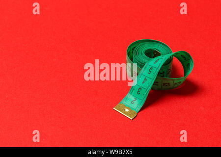 Perspective view of balled measuring tape on red background. Close up of slimming concept, Stock Photo