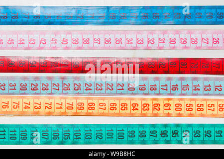 Close up of a group of colorful measure tapes lying in rows as a background. Diet concept on wooden background. Stock Photo