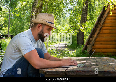 Bearded man freelancer work online on laptop. Business manager work on laptop. Bearded man using laptop for freelance work online outdoor. Stock Photo