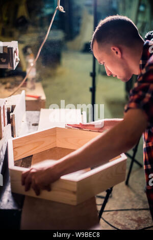 Young handsome joiner working with wood in his carpentry workshop, woodworker business owner Stock Photo