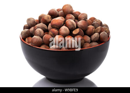 a bunch of raw hazelnuts in a black bowl isolated on a white background Stock Photo
