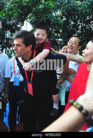 Timothy Shriver, Chairman and CEO of Special Olympics International, carries a Chinese boy on his back after the Youth Summit of the 5th Special Olymp Stock Photo