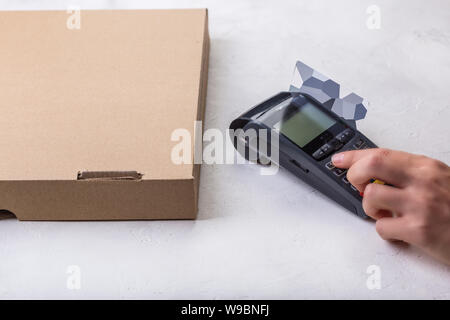 Using payment terminal with contactless credit card, cashless paying for pizza in restaurant Stock Photo