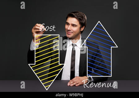 Businessman writing the concept of increased revenue and reduced cost Stock Photo