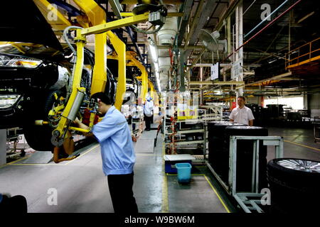 Chinese factory workers assemble Ford Focus cars on the assembly line ...