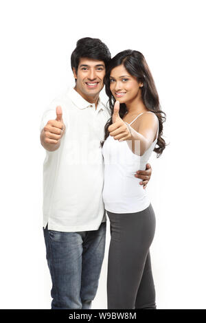 Young couple showing thumbs up sign and smiling Stock Photo