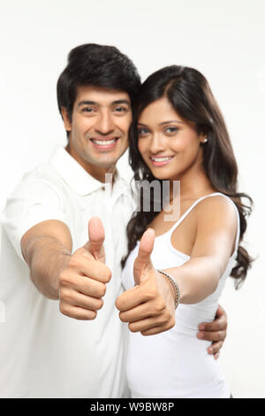 Young couple showing thumbs up sign and smiling Stock Photo