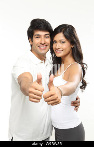 Young couple showing thumbs up sign and smiling Stock Photo