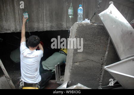 Chinese rescuers infuse physiological saline solution into a man being buried in the rubble after a viaduct collapsed in Zhuzhou city, central Chinas Stock Photo