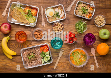 Healthy food in foil boxes on wooden background Stock Photo
