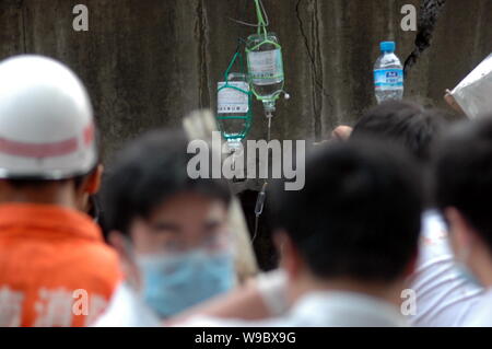 Chinese onlookers look at rescuers infusing physiological saline solution into a man being buried in the rubble after a viaduct collapsed in Zhuzhou c Stock Photo