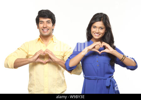 Young couple making heart shape with hands and smiling Stock Photo