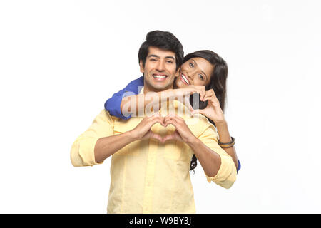 Young couple making heart shape with hands and smiling Stock Photo