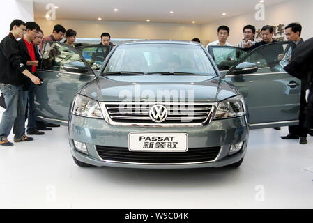 --FILE--Chinese visitors look at a Passat New Lingyu, manufactured by Shanghai Volkswagen, the joint venture of Volkswagen AG and SAIC (Shanghai Autom Stock Photo