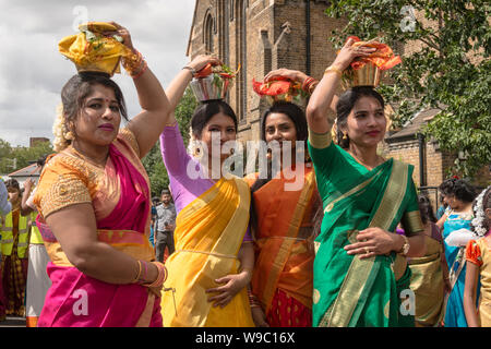 Devotees carrying pots of milk, known as“paal kudam, on their head during the annual Tamil Chariot Festival which passes St John's Church, West Ealing Stock Photo