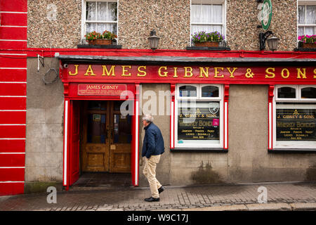 Ireland, Leinster, Fingal, Co Dublin, Malahide, New Street, man walking past door of James Gibney’s traditional Irish pub, Gibney & Sons Stock Photo