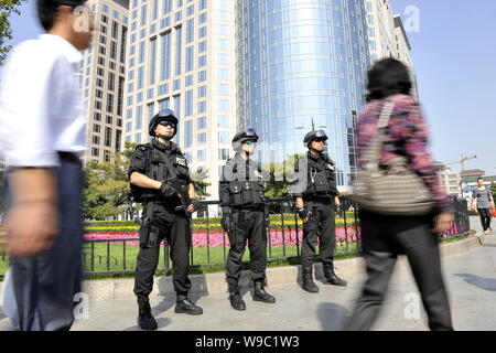 Local Chinese citizens walk past special police standing guard near the Wangfujing shopping street in Beijing, China, Wednesday, 23 September 2009. Stock Photo