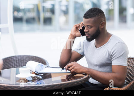 Serious african man checking financial plan data with collegues Stock Photo