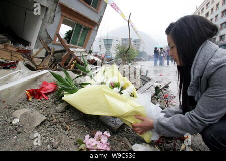 Huang Mei, 19, dedicates flowers in front of the debris of her former residence destroyed by the May 12 earthquake to mourn her family members who die Stock Photo