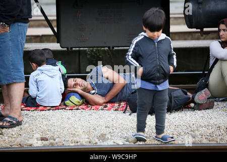 Dugo Selo, Croatia - September 17, 2015 : A group of Syrian refugees resting on the train tracks after arriving from Serbia and waiting for the buses Stock Photo