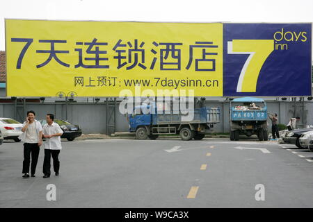 --FILE--Chinese men walk past a billboard of 7 Days Inn in Shanghai, China, 20 June 2007.   7 Days Group, the third largest economy hotel chain in Chi Stock Photo