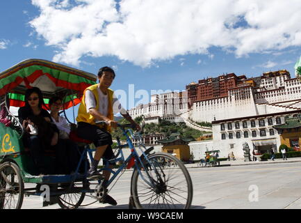 --FILE--A tricyclist rides tourists past the Potala Palace in Lhasa, southwest Chinas Tibet Autonomous Region, 8 September 2007.   Chinas Tibet Autono Stock Photo