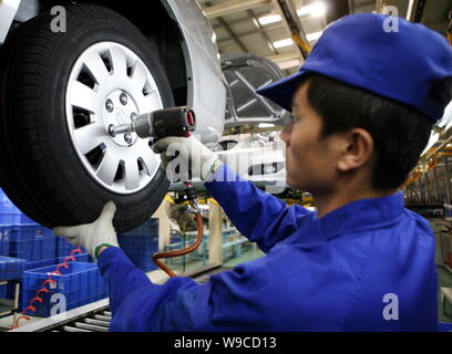 A Chinese factory worker assembles a car on the assembly line at an ...