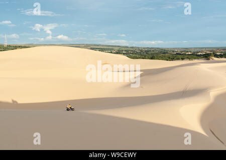 Mui Ne, Vietnam - June 2019: off-road ATV quad bike driving through desert sand dunes at sunrise. Stock Photo