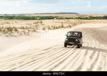 Mui Ne, Vietnam - June 2019: off-road vintage soviet car driving through desert sand dunes at sunrise. Stock Photo