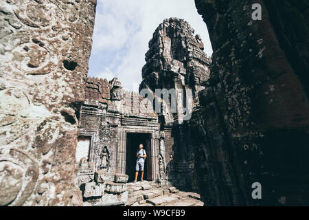 Caucasian man with camera standing among the ruins of Angkor Wat temple complex in Siem Reap, Cambodia. Stock Photo