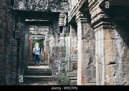 Caucasian blonde woman discovering the ruins of Angkor Wat temple complex in Siem Reap, Cambodia. Stock Photo