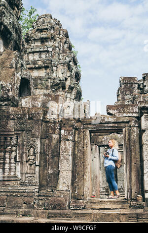 Caucasian blonde woman discovering the ruins of Angkor Wat temple complex in Siem Reap, Cambodia. Stock Photo