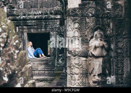 Caucasian blonde woman discovering the ruins of Angkor Wat temple complex in Siem Reap, Cambodia. Stock Photo