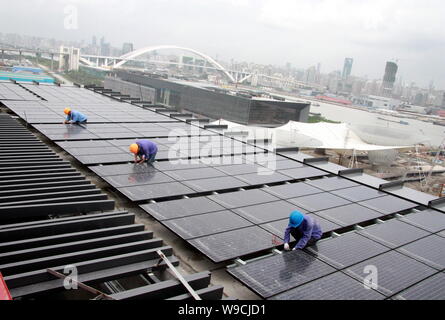 Chinese workers install solar panels on the rooftop of the China Pavilion at the Shanghai Expo site in Shanghai, China, 1 September 2009.   Installati Stock Photo