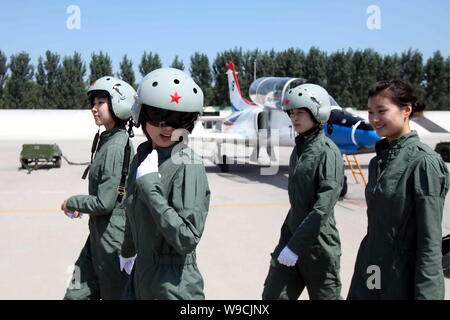 Young female fighter plane pilots of Chinese PLA Air Force walk past training planes after a new flight suits delivery ceremony at an airport in Tangs Stock Photo