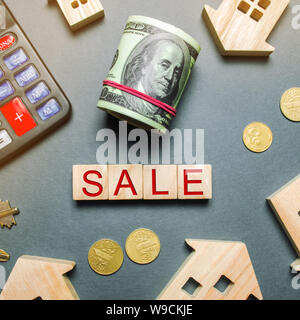 Table with wooden houses, calculator, coins, magnifying glass with the word Sale. Property For Sale. Sell an apartment or house. Housing for sale. Rea Stock Photo