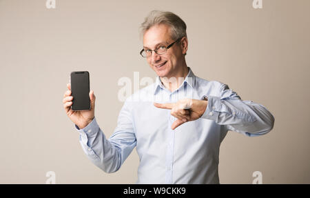 Senior man presenting smartphone and pointing on it Stock Photo
