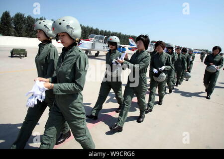 Young female fighter plane pilots of Chinese PLA Air Force walk past training planes after a new flight suits delivery ceremony at an airport in Tangs Stock Photo